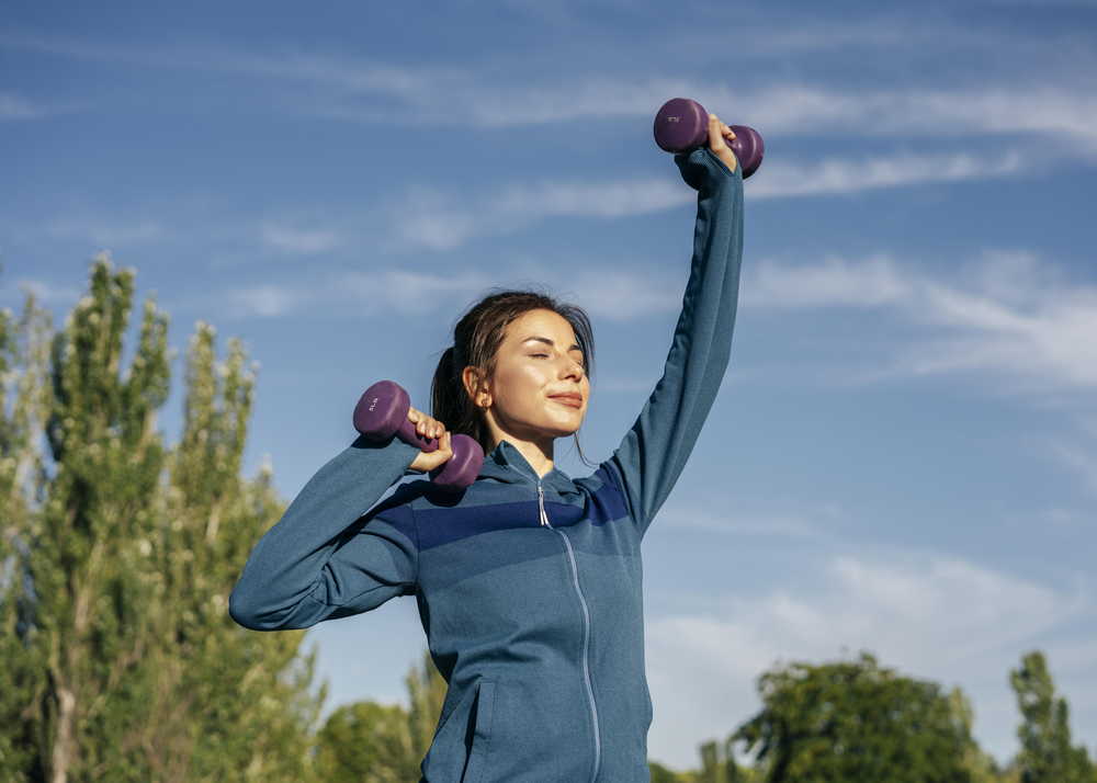 medium shot woman practicing with dumbbells