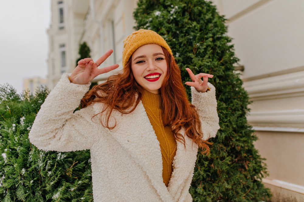 elegant ginger young lady enjoying winter pleased red haired girl posing with peace sign outdoor