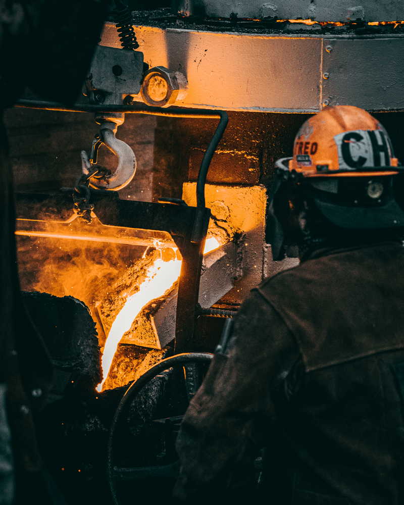 vertical shot adult industrial worker uniforms melting metal factory
