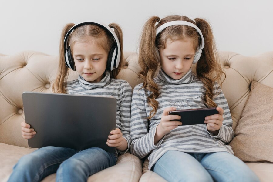 cute twins using digital devices 23 2148771419 1