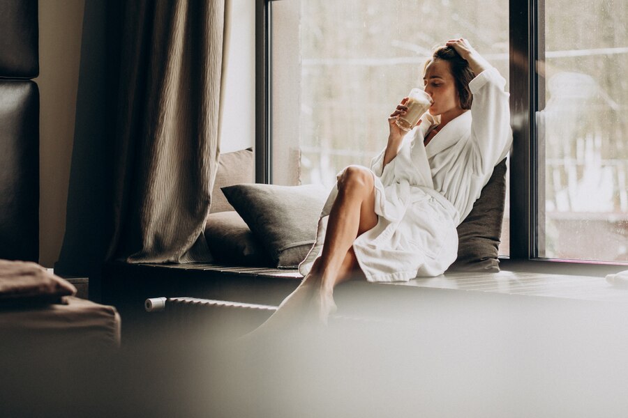 woman drinking coffee bathrobe by window home 1303 20243