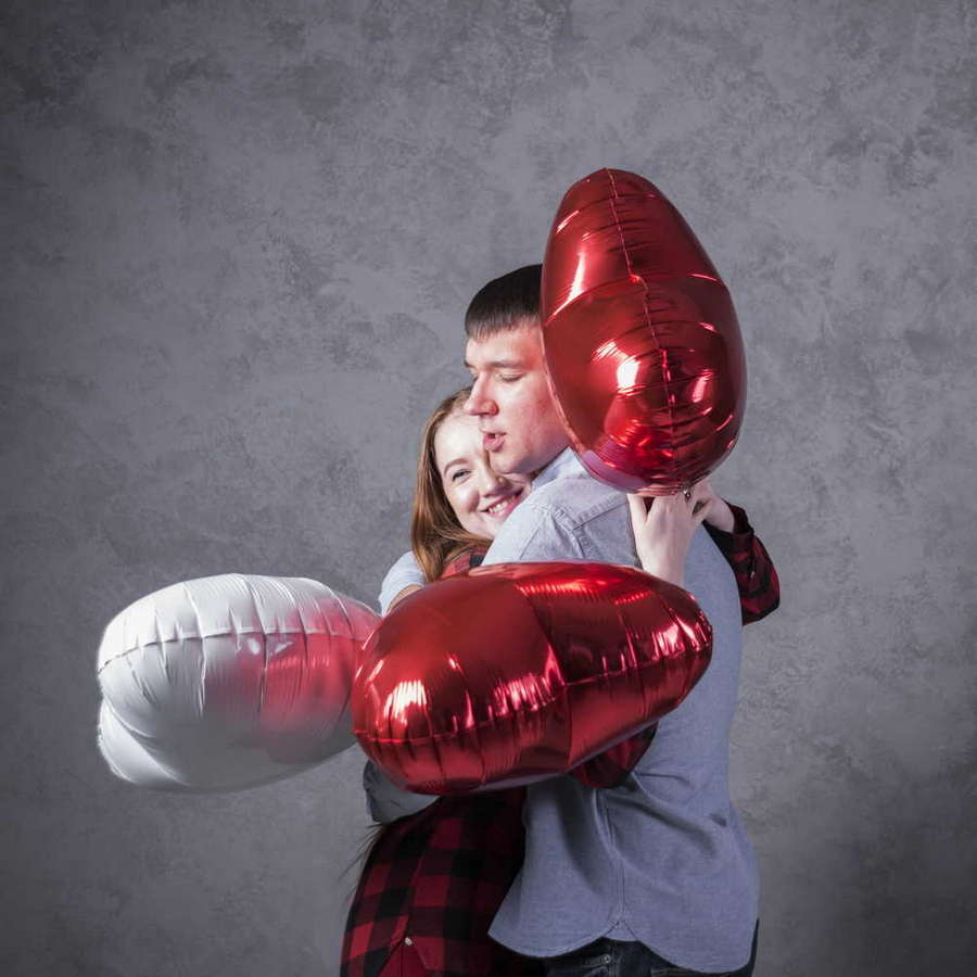 couple with balloons heart shape hugging