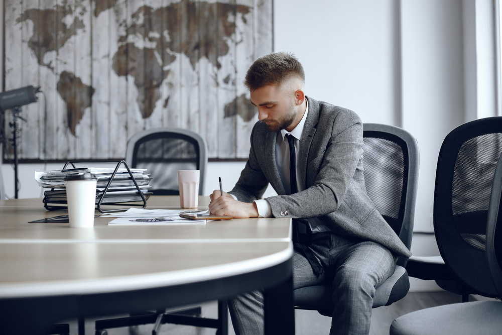 man is sitting table guy business suit businessman signs thedocuments