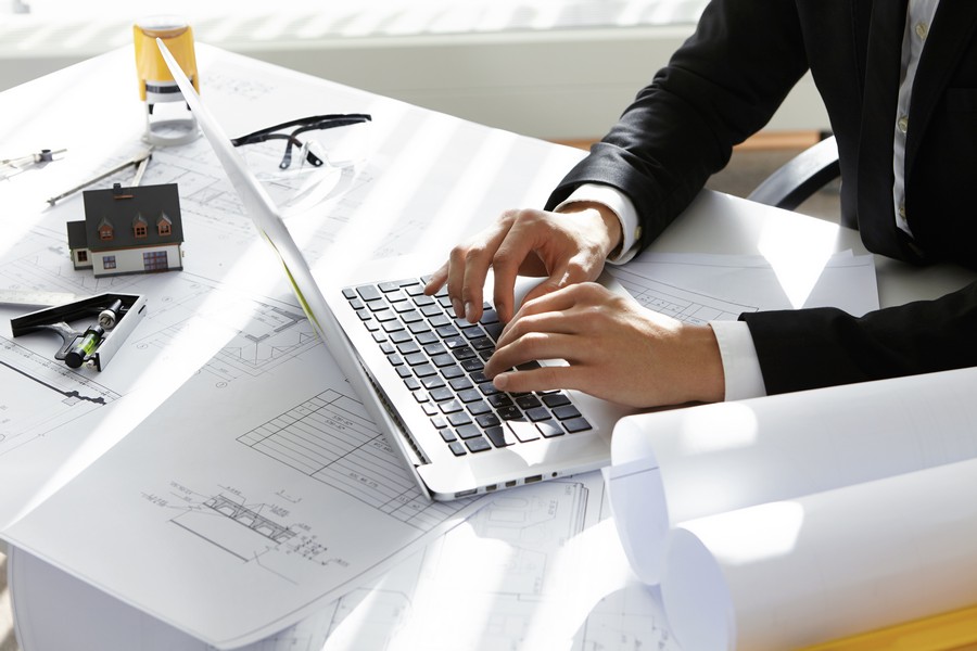 hands ceo construction company black suit typing message via e mail partners laptop with drawings seal stamp divider table