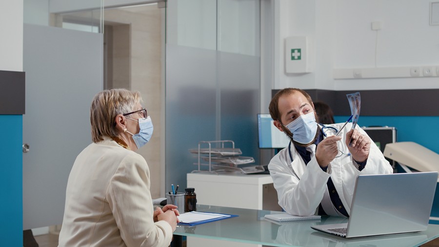 Кому доверить здоровье? Руководство по выбору частной клиники 2 male doctor analyzing radiography scan with elder patient checkup visit physician explaining x ray results bones diagnosis retired woman medical office pandemic